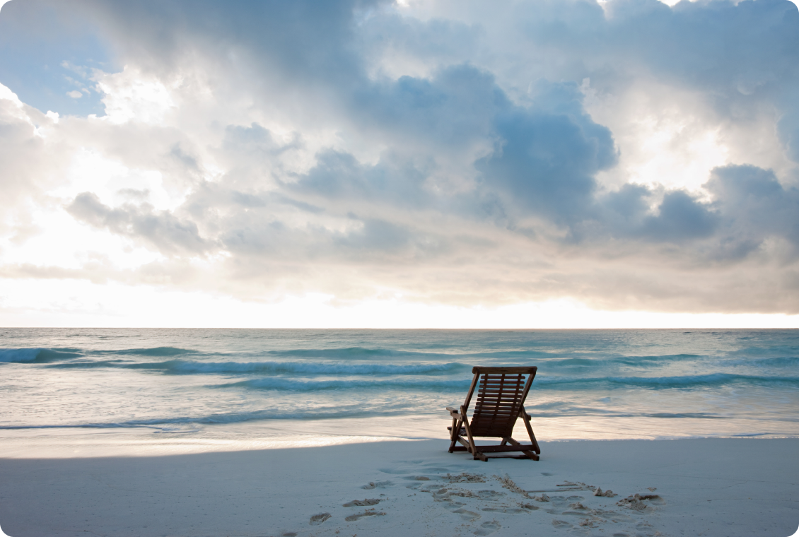 Beach chair facing ocean under cloudy sky